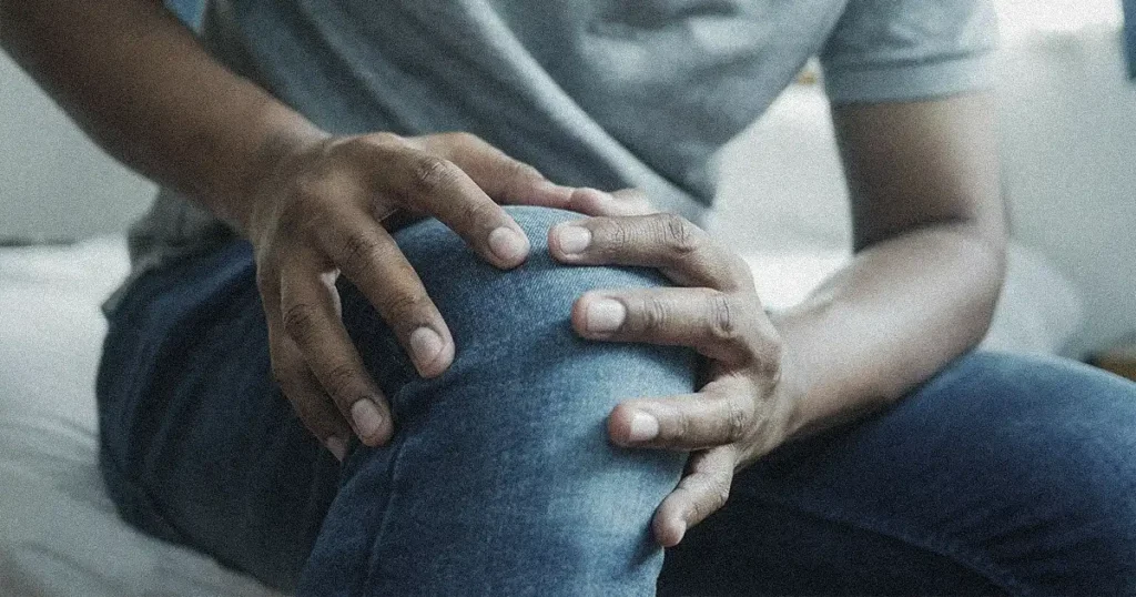 A man is having knee pain while sitting on a couch