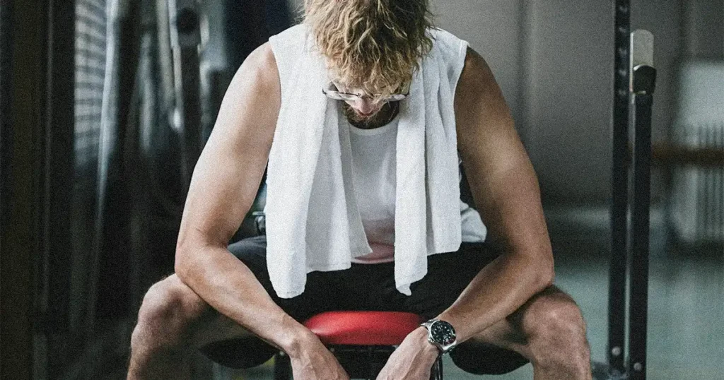 Exhausted man sitting on a bench in the gym